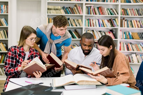 Preview: Smart confident young multiethnical students reading books at the table, looking for information and