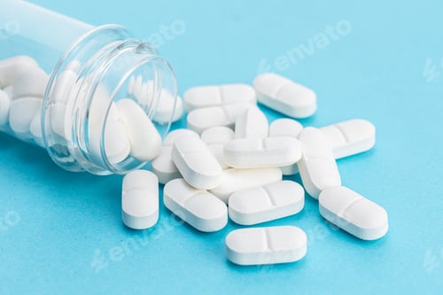 Preview: White medicine pills spilling from a container on blue background