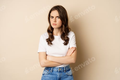 Preview: Offended angry woman cross hands on chest, frowning and sulking insulted, standing over beige