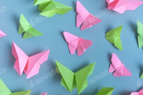 Preview: Paper butterfies green and pink color flat lay on colored background