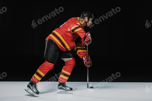 Preview: side view of young professional sportsman playing ice hockey on black