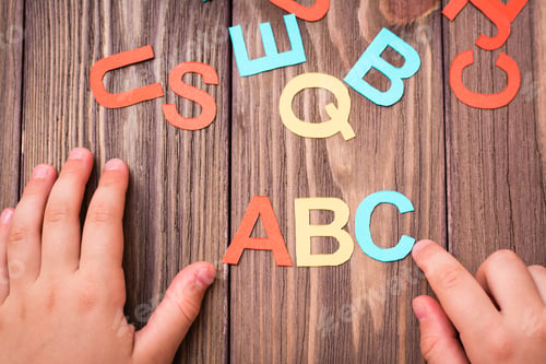 Preview: Children`s hands make up the word "ABS" from colored carved cardboard letters on a wooden background