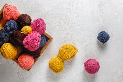 Preview: Balls of yarn in different colors with knitting needles.