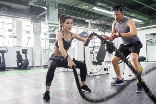 Preview: Young woman working with trainer at gym