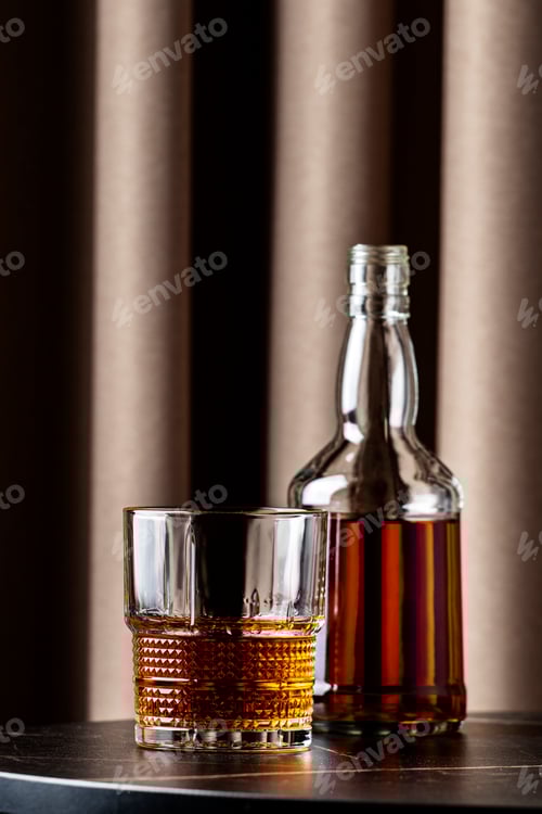 Preview: glass of rich bourbon whiskey alongside a bottle in a cozy setting with warm curtains