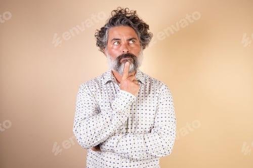 Preview: Middle-aged grey-haired man in casual clothes with a finger on his chin thinking. A doubt concept.