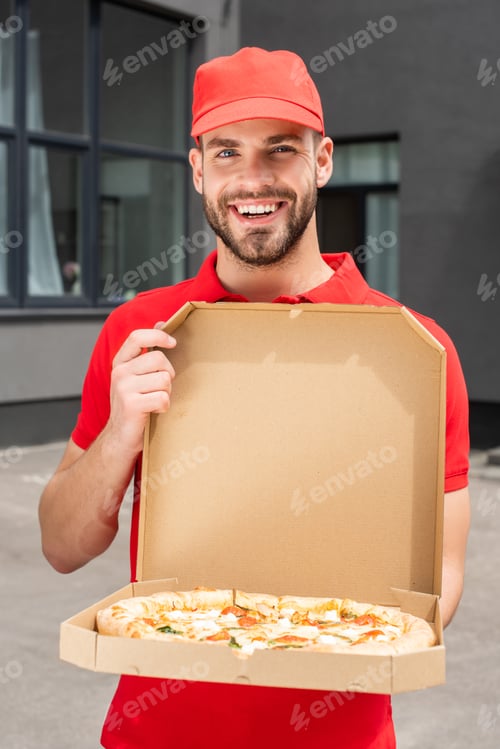 Preview: smiling caucasian delivery man holding box with pizza