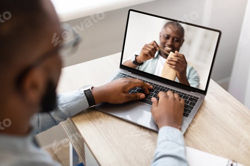 Preview: Young man watching online DIY class, participating in woodworking workshop, using laptop at home