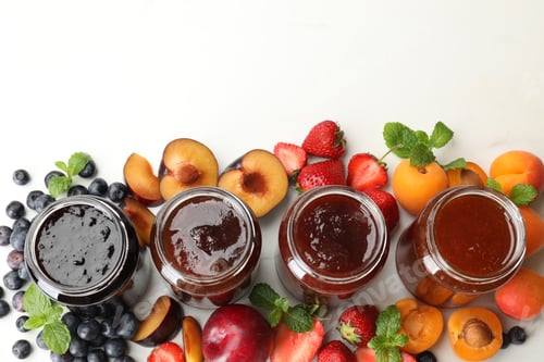 Preview: Different jams in jars and ingredients on white background, flat lay. Space for text