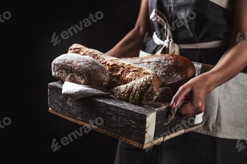 Preview: Bread in an old wooden box in the hands of a baker. Homemade pastries, rural style