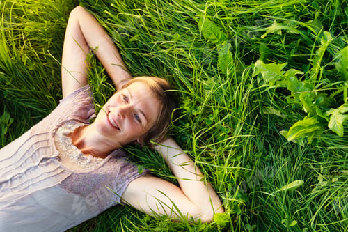 Preview: Woman relaxing in tall green grass outdoors