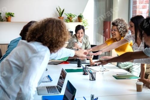 Preview: Group of multiracial coworkers join hands to celebrate teamwork success.