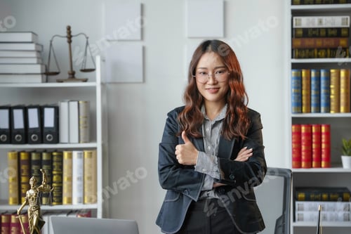 Preview: Confident asian lawyer in office, giving thumbs up, surrounded by law books
