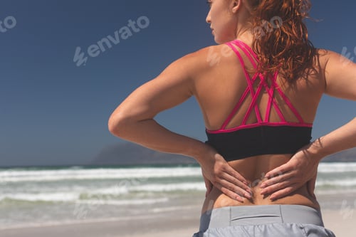 Preview: Fit woman standing with hand behind back at beach