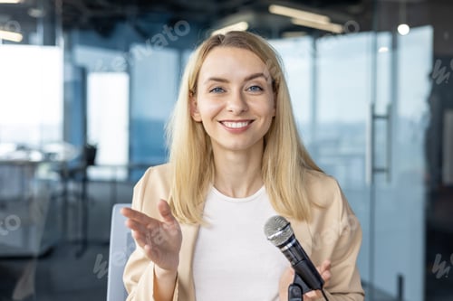 Preview: Smiling businesswoman holding a microphone during a presentation in a modern office