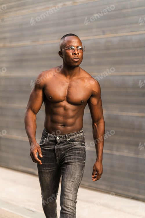 Preview: Vertical shot of a fit sexy attractive black shirtless male in jeans and sunglasses posing