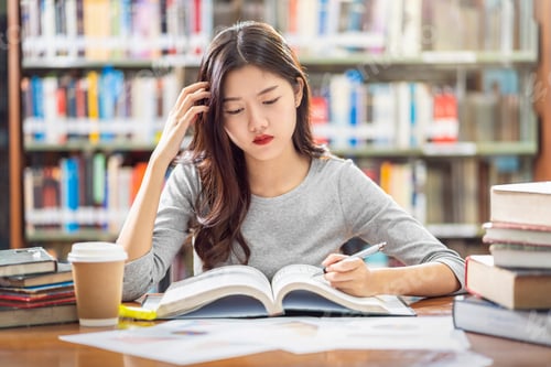 Preview: Asian young Student in casual suit reading and doing homework in library of university