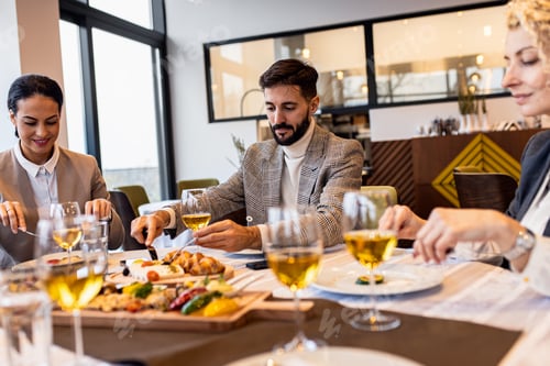 Preview: Smiling coworkers in restaurant talking during business lunch.
