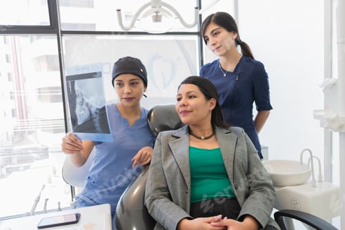 Preview: Young female dentist checking x-ray of a patient.