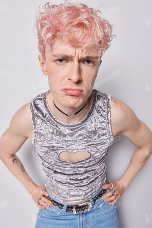 Preview: Vertical shot of displeased pink haired guy has non tradiotional orientation frowns face feels
