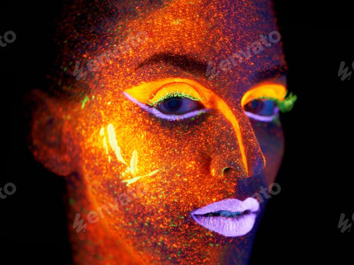 Preview: Ready for the nightlife. Portrait of a young woman with with neon paint on her face posing.