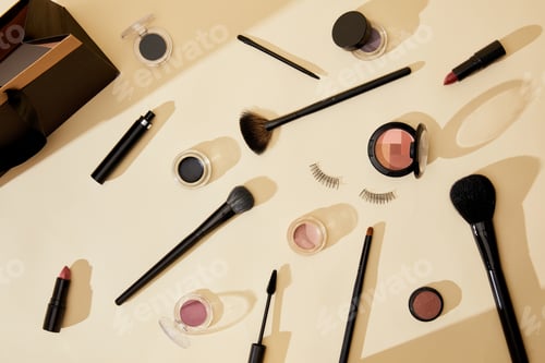 Preview: top view of different cosmetics and false eyelashes lying on beige tabletop