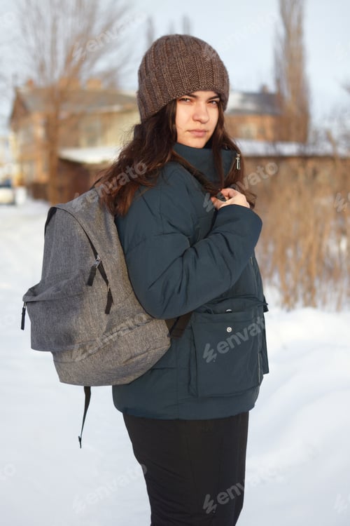Preview: Outdoors in winter, a young woman with a backpack on her shoulder, turned her face to the camera.