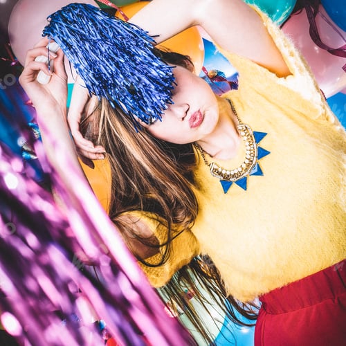 Preview: Girl standing in front of funky background with colourful clothes and ballons