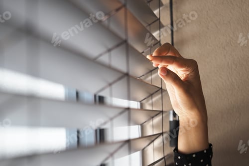 Preview: Hand adjusting blinds in a bright indoor space