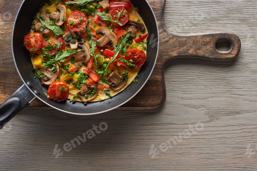 Preview: top view of homemade omelet in frying pan on wooden board