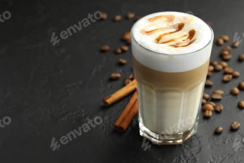 Preview: Tasty latte macchiato in glass, coffee beans and cinnamon on black table, closeup. Space for text