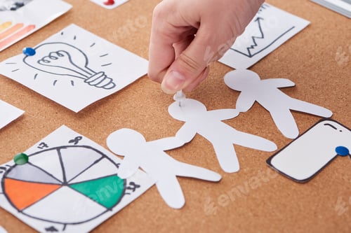 Preview: cropped view of woman pinning paper craft decoration on cork board