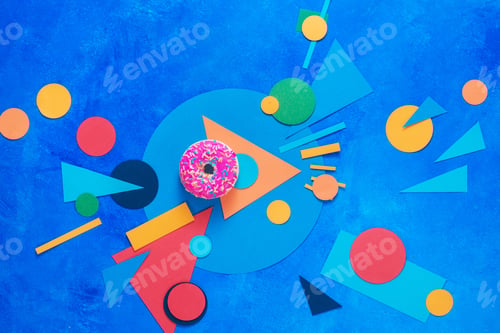Preview: A pink donut with colorful paper decorations. Color blocking flat lay with sweets. Complementary