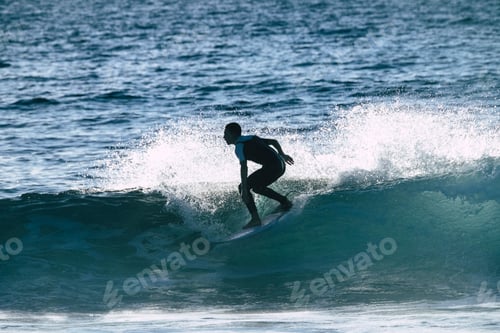 Preview: teenager surfing at the wave in tenerife playa de las americas - white and black wetsuits