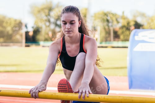 Preview: Female athlete stretching on an athletics track.