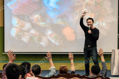 Preview: Rear view of Audience showing hand to answer the question from Speaker on the stage