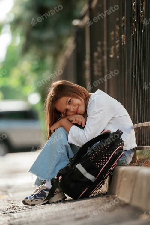 Preview: On the sidewalk. Schoolgirl with backpack is outdoors