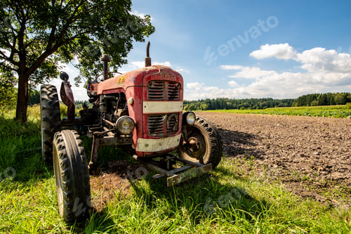 Preview: Old red rusty tractor in a field