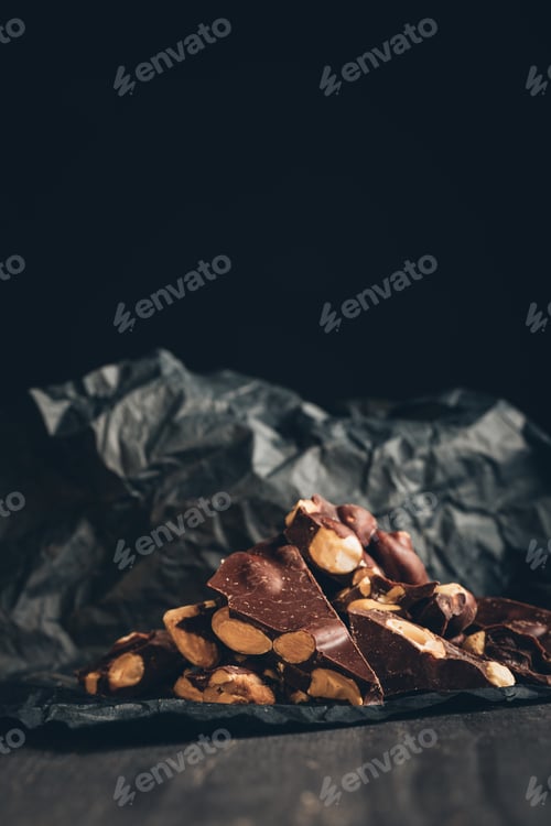 Preview: appetizing chocolate with nuts pieces on dark gray crumpled paper