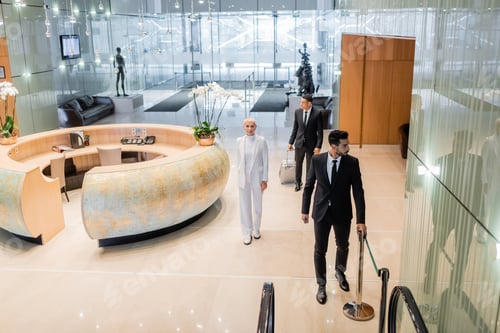 Preview: high angle view of multiethnic bodyguards in formal wear escorting senior business lady in luxury