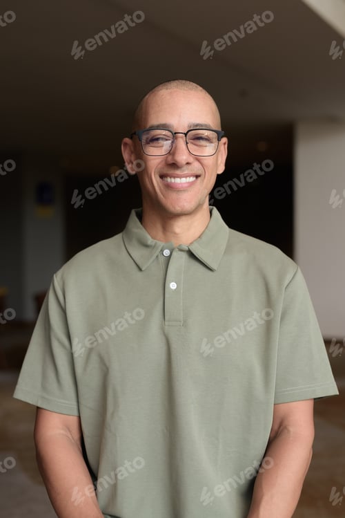 Preview: Bald Hispanic man in hotel lobby with eyeglasses, stylish confident portrait in casual setting