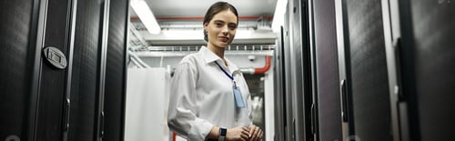 Preview: Woman in a white shirt oversees server operations in a sleek data center, ensuring security, banner