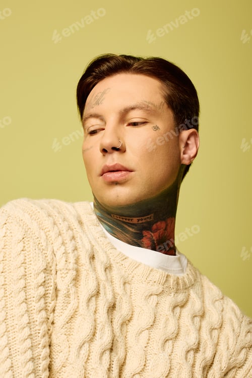 Preview: Young man with distinctive tattoos poses thoughtfully against a vibrant yellow backdrop