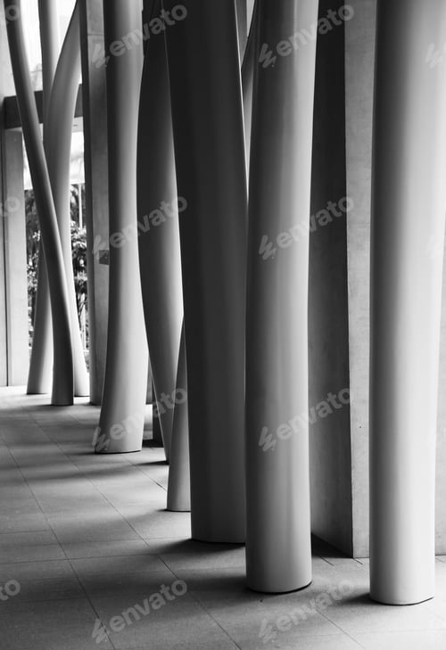 Preview: Vertical grayscale shot of a modern building's interior with crooked columns
