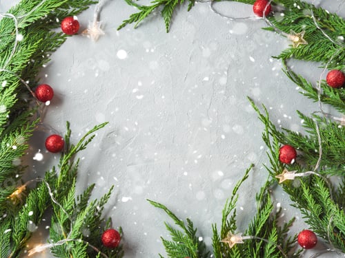 Preview: Green fir tree branches frame with star shape Christmas lights and red ornament decor