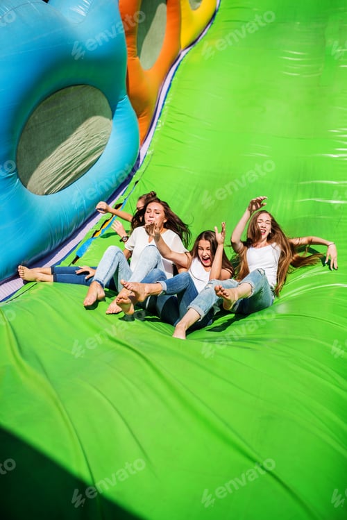 Preview: Gorgeous girls having fun on a slide on a sunny day.
