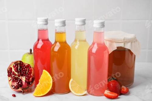 Preview: Delicious kombucha in glass bottles, jar and fresh fruits on white marble table