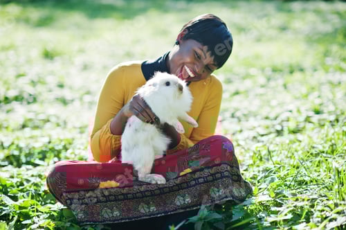 Preview: African american girl at yellow and red dress with white rabbit at hands.