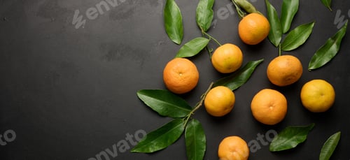 Preview: A ripe clementine with green leaves on a black table, top view