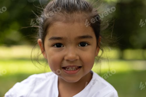 Preview: Closeup portrait of latina girl smiling, with park vegetation background.